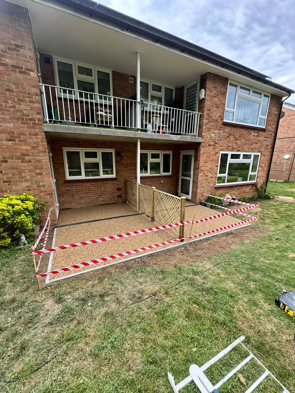 Completed tan resin-bound area within timber edging at a shared brick apartment garden
