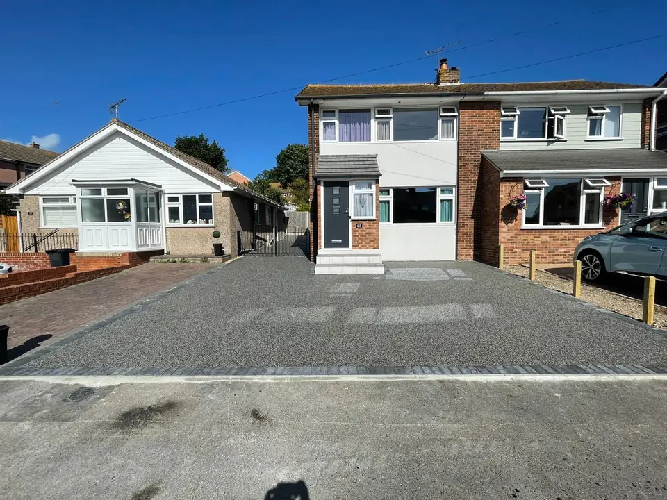 Finished grey resin-bound driveway in front of neighbouring houses with contrasting edging