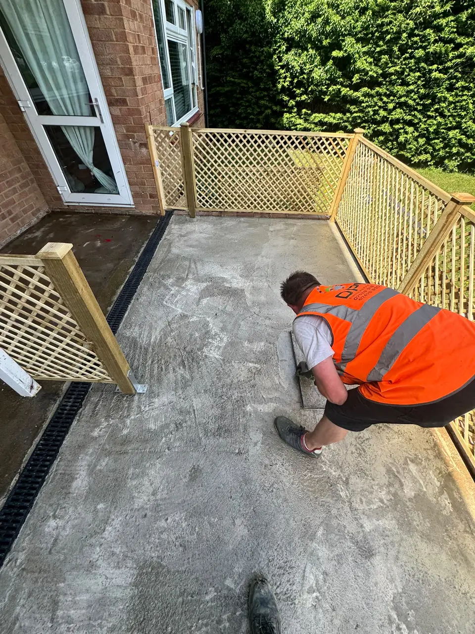 DPK installer working on a prepared surface beside a garden threshold