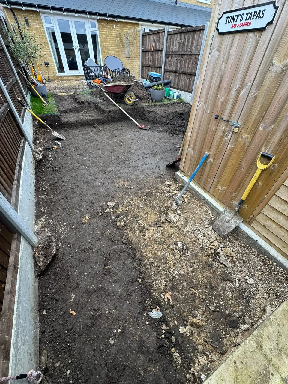 Garden soil excavated and tools on site while preparing the porcelain patio