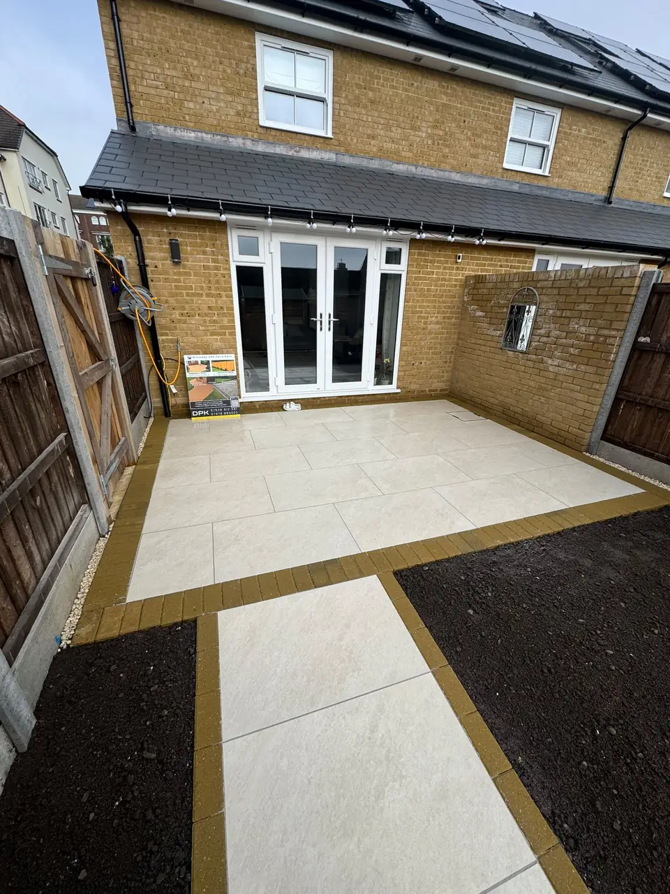 Pale porcelain patio with contrasting brick edging and a paved path