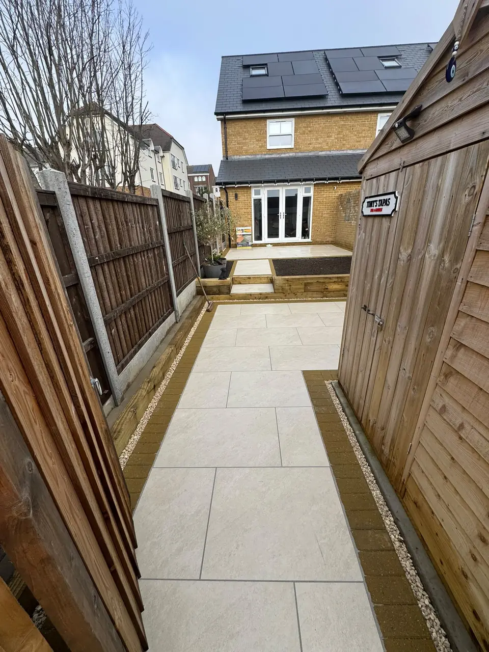 Porcelain-paved path with contrasting edging leading through a Gravesend garden
