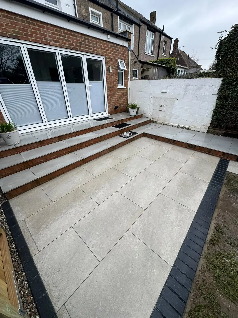 Pale porcelain paving across a garden patio with several finished steps