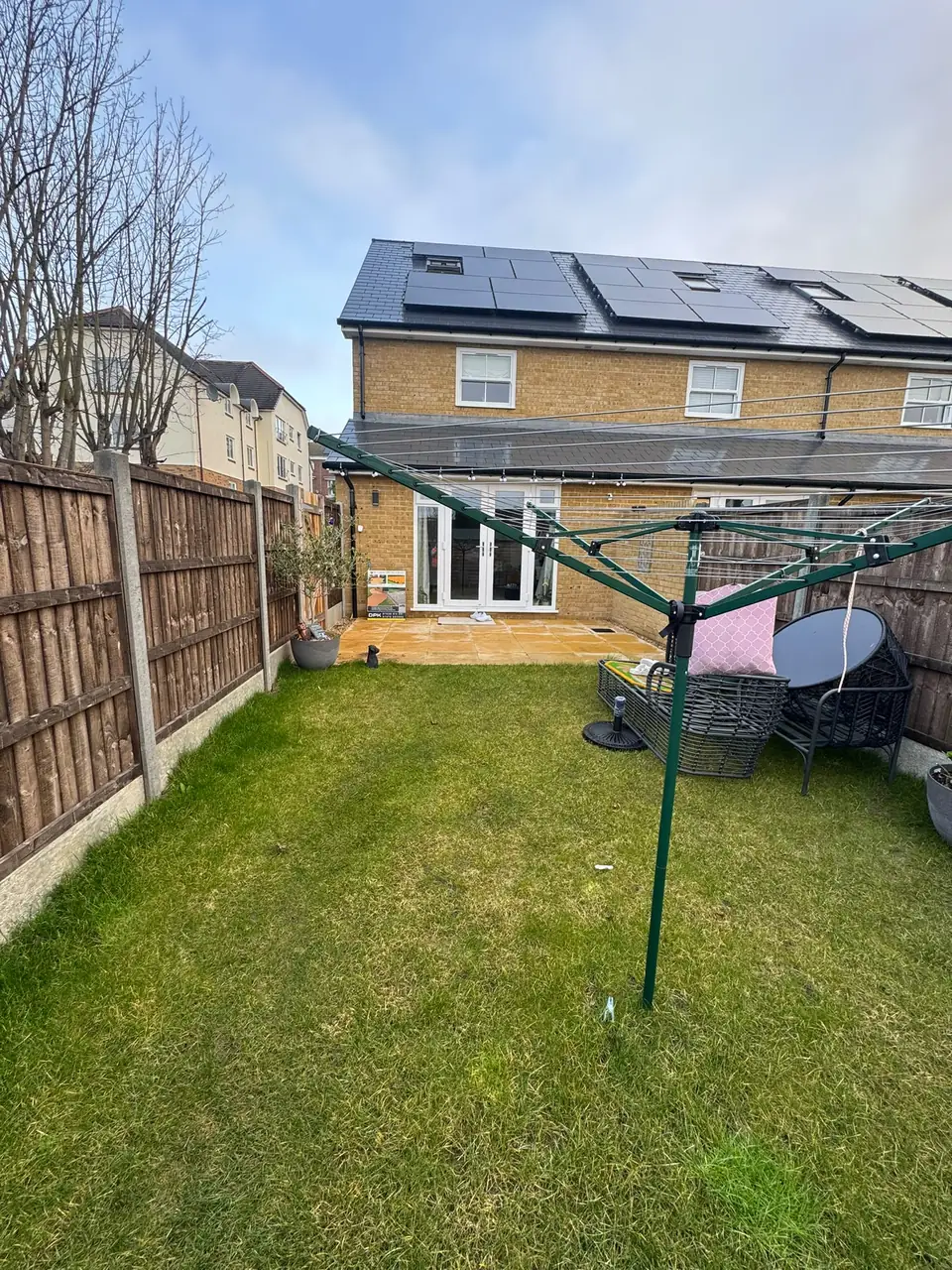 Grassed rear garden with a small paved area before the porcelain patio project