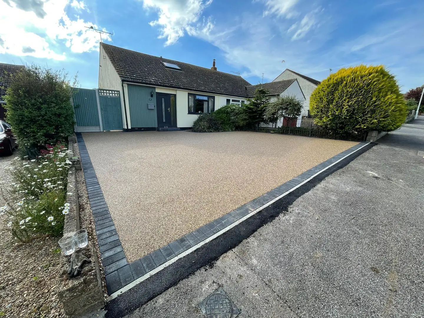 Tan resin-bound driveway with dark block edging outside a house