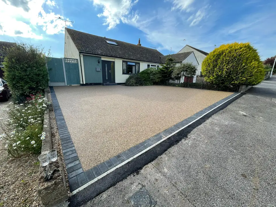 Tan resin-bound driveway with dark block edging outside a house